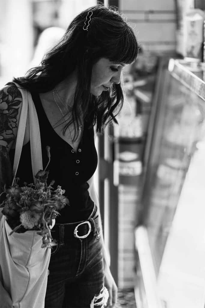 A woman holding a bag of food and flowers.