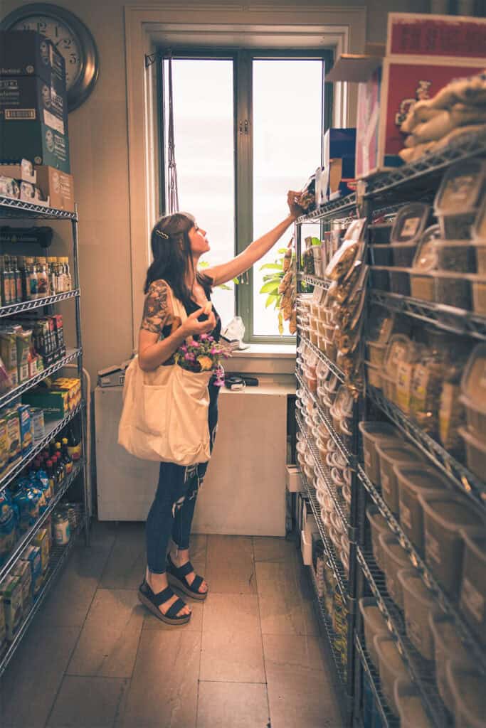 A woman holding a bag of food and flowers.