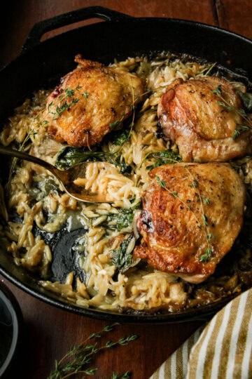 a skillet with chicken and orzo