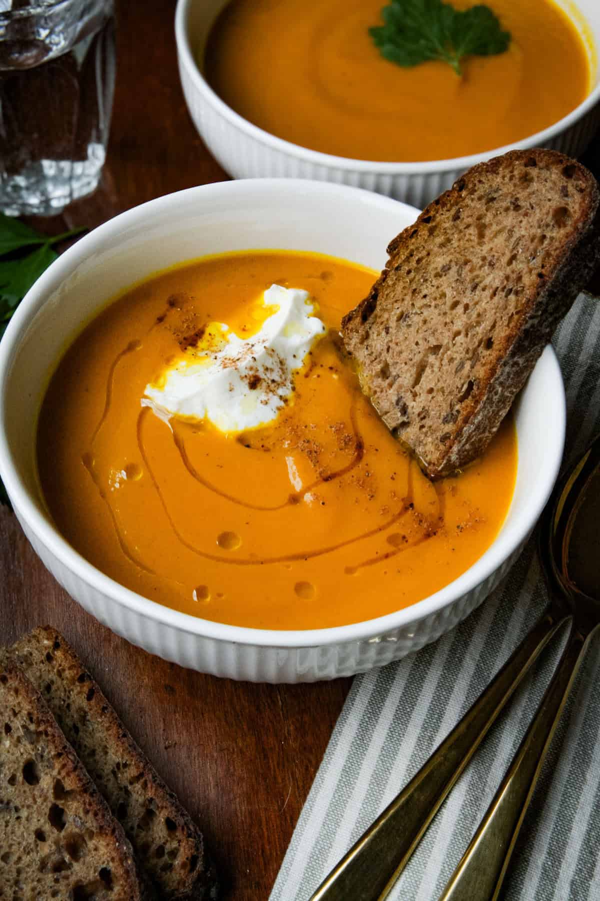 a bowl of carrot soup with bread