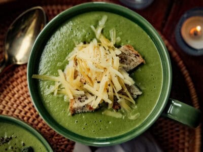 a bowl of broccolini soup surrounded by candles